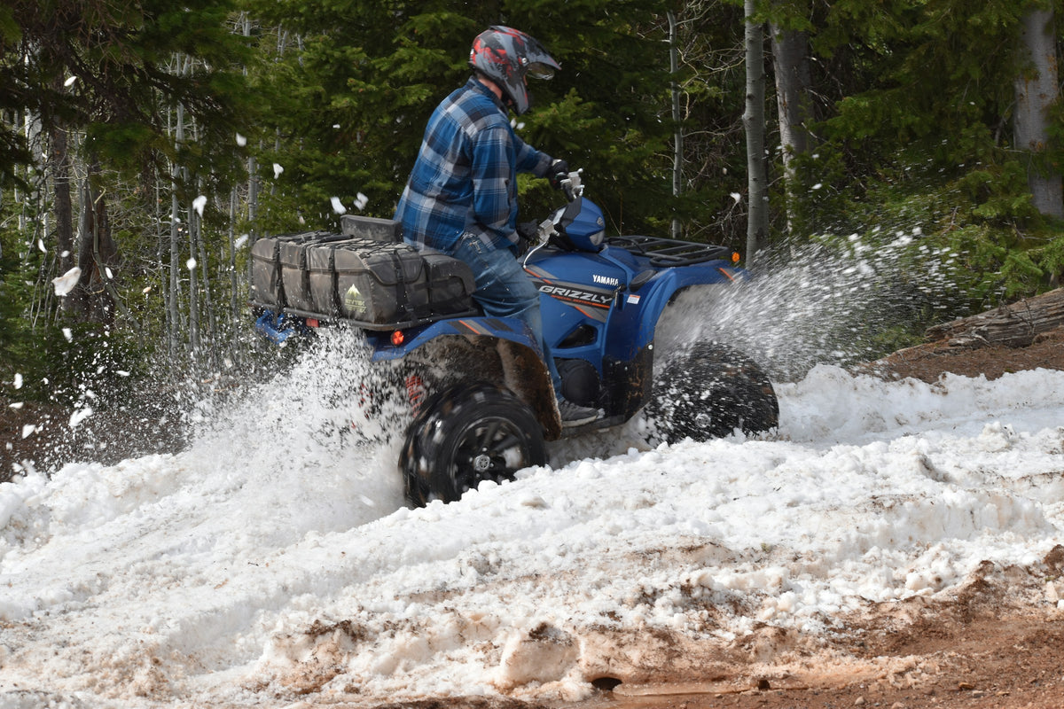 Pilote de VTT qui soulève la neige dans un sentier en forêt